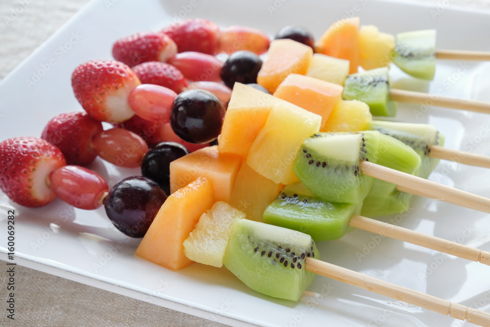 fresh rainbow fruit skewers on white plate