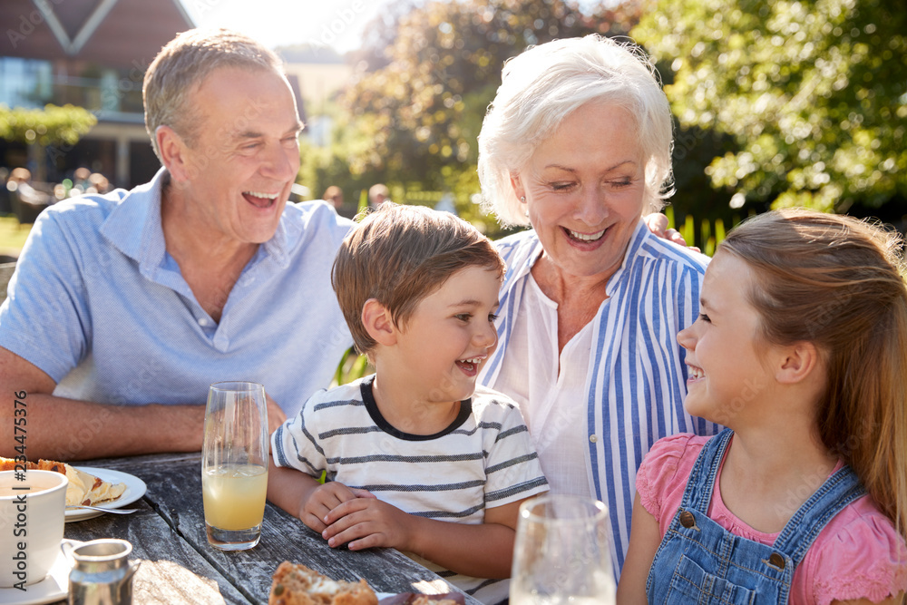 Grandparents With Grandchildren Enjoying Outdoor Summer Snack At Cafe