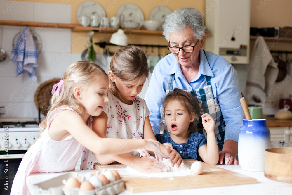 Home cooking. Family and kids make bread for dinner in cozy kitchen. Grandmother and funny little girls preparing homemade food. Children chef concept. Lifestyle authentic moments. Real, true emotions