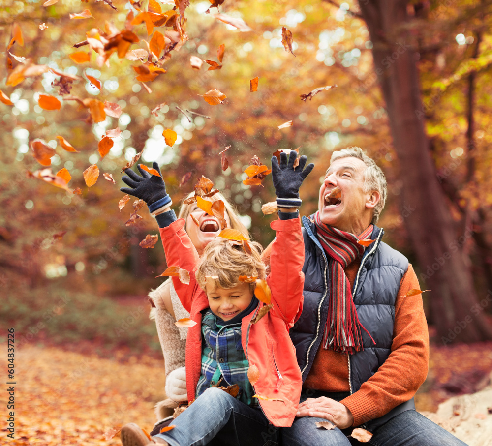 Older couple playing with grandson in autumn leaves