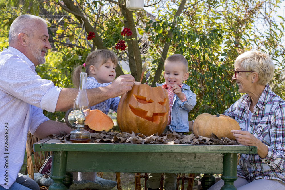 Grandparents with grandchildren carving pumpkin together