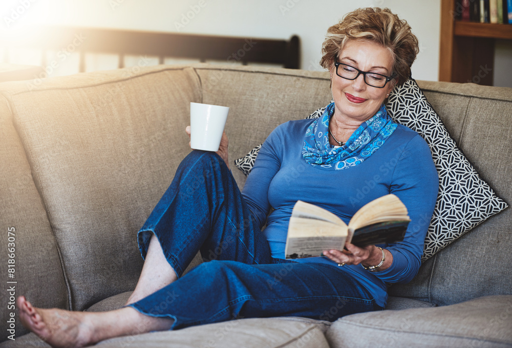 Happy, senior woman and glasses with book or story with coffee for literature in retirement home. Grandma, drink and reading hobby for peace, relax and comfort on sofa for entertainment and knowledge