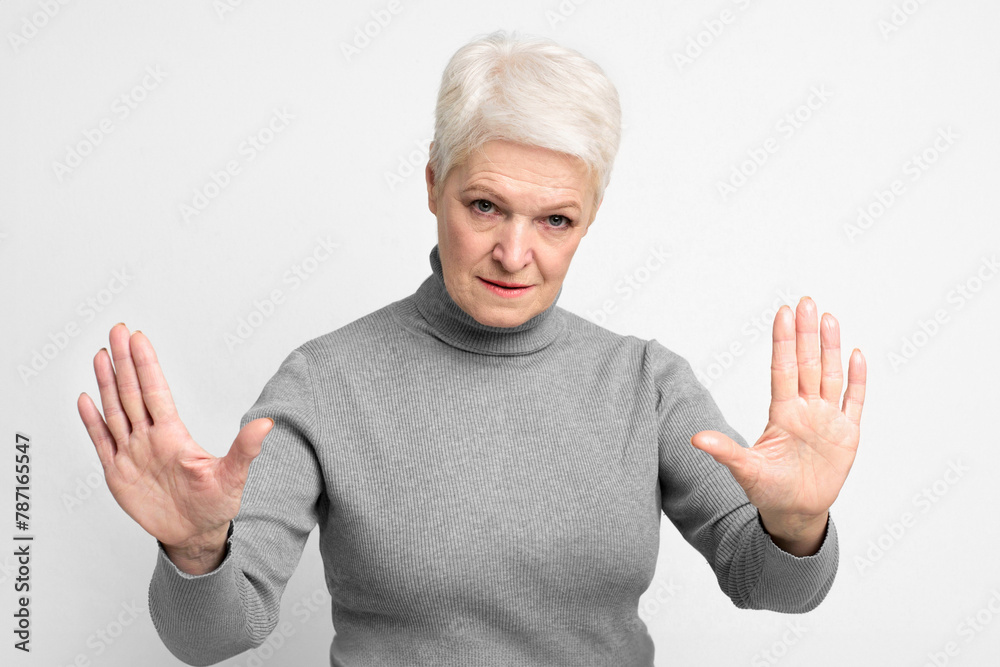 Senior woman with arms raised in a stop sign